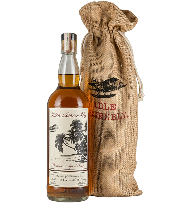 Idle Assembly Rum bottle with tropical label next to branded burlap bag for spirits and liqueurs gift set