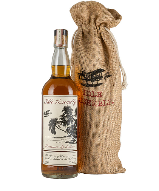 Idle Assembly Rum bottle with tropical label next to branded burlap bag for spirits and liqueurs gift set