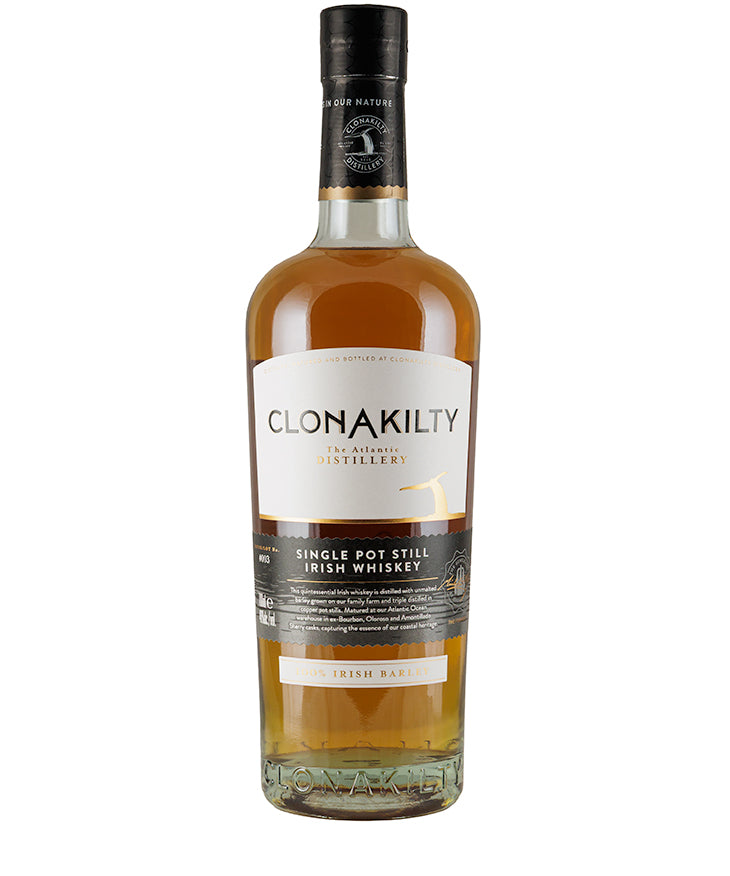 Bottle of Clonakilty Single Pot Still Irish Whiskey with amber liquid and black cap against white background