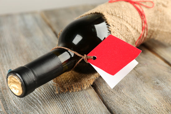 A wine bottle with a red gift tag around the neck